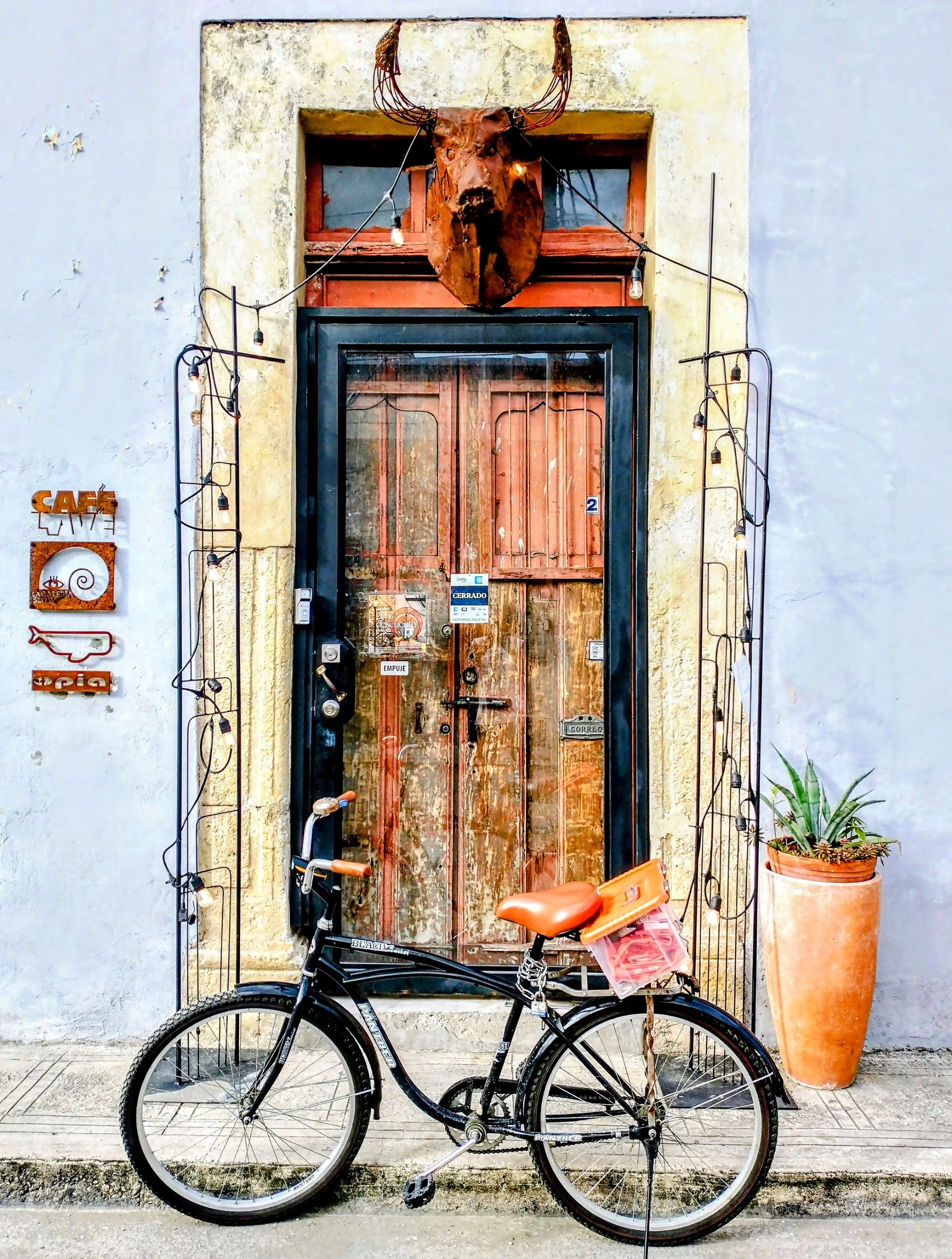 Colorful entrance of a boutique café in Mérida featuring a vintage bicycle and rustic decor.